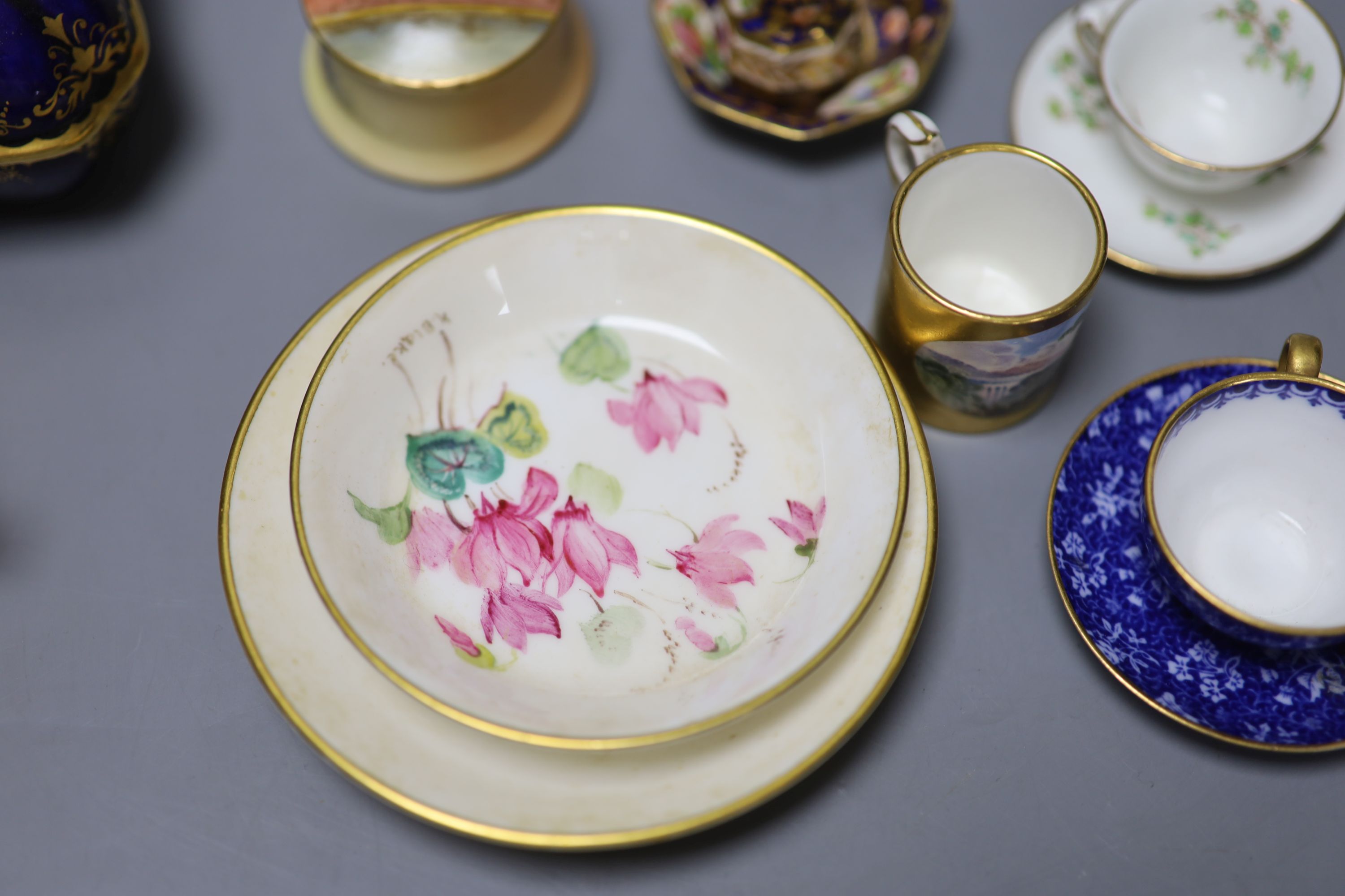 An early 20th century Coalport box and cover painted with a bird on a blue ground, a Coalport miniature gilt ground mug with landscape,